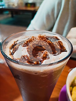 Cold ice milkshake with chocolate syrup topping on top