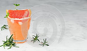 Cold lemonade of fresh grapefruit juice with alcohol or wihtout alcohole and ice cubes decorated a slice of grapefruit, twig mint