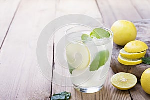 Cold lemonade in a glass with lemon Ice and mint Placed on an old wooden table photo