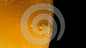 Cold light beer in a glass with water drops rotates. Beer mug close up on a black background.