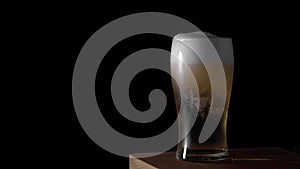 Cold light beer is poured into a glass with water drops ever matte black background, border design. Craft Beer close up
