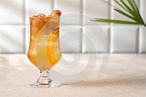 Cold longan juice with ice in a glass, on the dining table decorated by the window with evening light