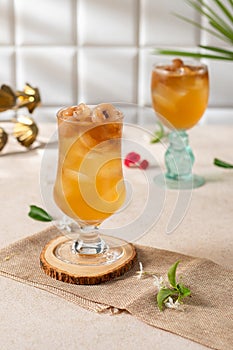 Cold longan juice with ice in a glass, on the dining table decorated by the window with evening light