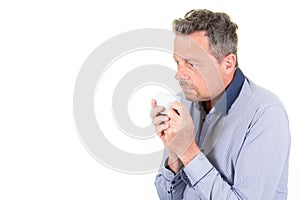 Cold man in blue shirt holding Coffee mug looking down hot drink cup pensive he is refrigerated in white background