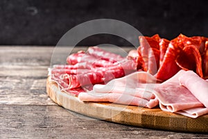 Cold meat on cutting board on wooden table. Ham, salami, sausage mortadella and turkey