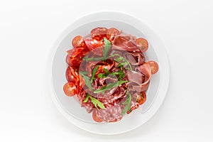 Cold meat plate with ham, proscuitto and salami served with cherry tomatoes top view on a white background. Spanish meat