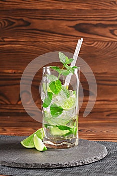 Cold mojito with ice and lime. Green mojito with rum or liquor on a wooden background. Refreshing alcoholic drinks. Copy space.