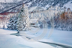 Cold morning scene of frozen rive and white wooden house on backgroundr.