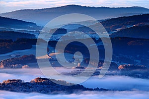 Cold morning in Sumava National park, hills and villages in the fog and rime, misty view on czech landscape, blue winter scene, Tr