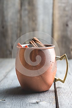 Cold Moscow Mule cocktail in copper mug on the rustic background