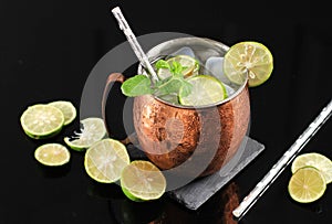 Cold Moscow Mule Coctail on Copper Mug  with Ginger Beer, Lime,  and Vodka, Garnish with Mint Leaf. Isolated on  Black Slate