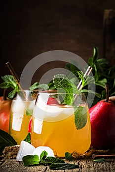 Cold pear juice, iced summer non-alcoholic cocktail with mint, old wooden table background, selective focus