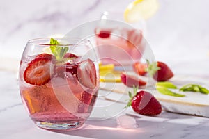 Cold pink strawberry flavoured jin and tonic garnished with fresh fruits and mint leaves