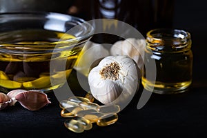 Cold pressed garlic oil in bowl with  garlic oil capsule on dark background.