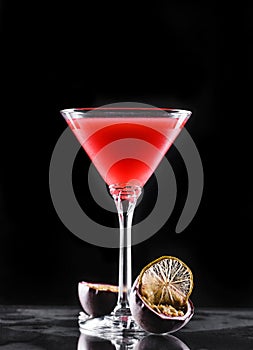 Cold red cocktail with passion fruit in tall glass on black background. Summer drinks and alcoholic cocktails