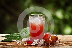 Cold red grape juice on natural green background, selective focus