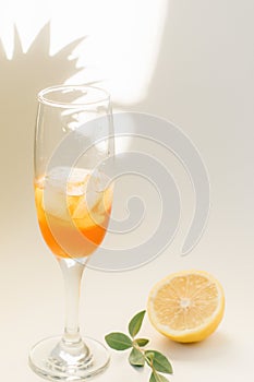 Cold refreshing drink with lemon orange slices by the glass on white background on directly sunlight with shadows