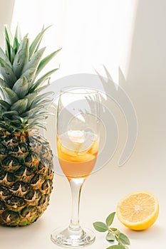 Cold refreshing drink with lemon orange slices by the glass on white background on directly sunlight with shadows