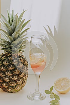 Cold refreshing drink with lemon orange slices by the glass on white background on directly sunlight with shadows