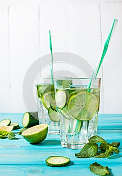 Cold and refreshing infused detox water with lime, mint and cucumber in a glass on wood background