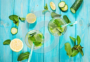 Cold and refreshing infused detox water with lime, mint and cucumber in a glass on wood background