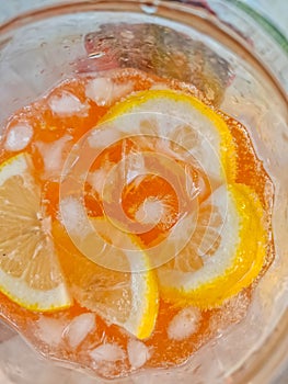 Cold refreshing limonade, gin tonic in glass, with fresh mint and ice cubes, lime and lemon on wooden table. Summer