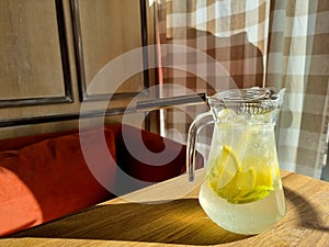 Cold refreshing limonade, mojito or gin tonic in glass, with fresh mint and ice cubes, lime and lemon on wooden table