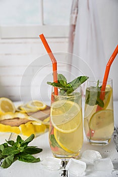 Cold refreshing summer drink with lemon and mint on wooden background