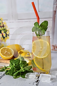 Cold refreshing summer drink with lemon and mint on wooden background