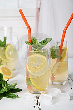 Cold refreshing summer drink with lemon and mint on wooden background