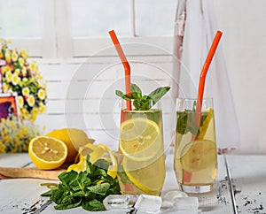 Cold refreshing summer drink with lemon and mint on wooden background