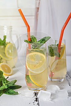 Cold refreshing summer drink with lemon and mint on wooden background