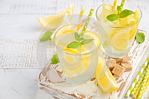 Cold refreshing summer drink with lemon and mint on wooden background.