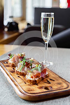 Platter: cold salmon bruschetta and greens with a glass of champagne