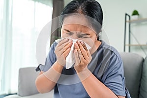 Cold sick woman got nose allergy cough or sneeze with tissue paper sitting on the sofa. Healthcare and medical concept