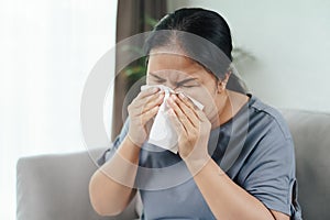 Cold sick woman got nose allergy cough or sneeze with tissue paper sitting on the sofa. Healthcare and medical concept