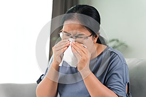 Cold sick woman got nose allergy cough or sneeze with tissue paper sitting on the sofa. Healthcare and medical concept