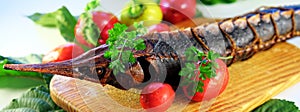 Cold smoked red fish sterlet selective focus with a head decorated with green tomatoes and olives. on a festive set