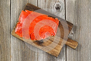 Cold Smoked Red Salmon on wooden server board with rustic wood b