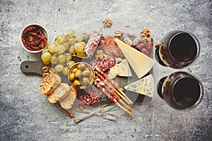 Cold snacks board with meats, grapes, wine, various kinds of cheese