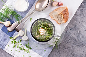 Cold Soup Okroshka in enamel cup and raw ingredients on grey stone table