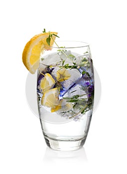 Cold sparkling water with ice and flowers decorated with slice of lemon