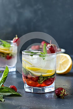 Cold strawberry mojito drink with strawberry, lemon slices and mint, vertical photo