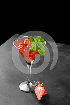 Cold summer strawberry cocktail mojito, margarita, daiquiri in a martini glass on black background, close up