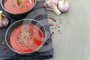 Cold tomato gazpacho soup in a deep plate on a stone background.