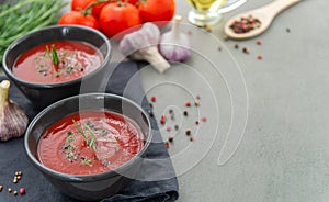 Cold tomato gazpacho soup in a deep plate on a stone background.