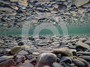 Cold underwater river bed with perfect reflection on surface