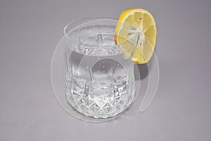A cold water glass with lemon on white.