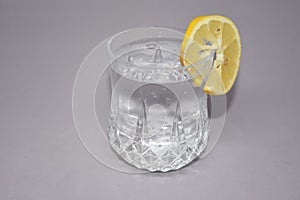 A cold water glass with lemon on white.