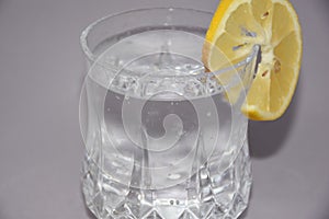 A cold water glass with lemon on white.